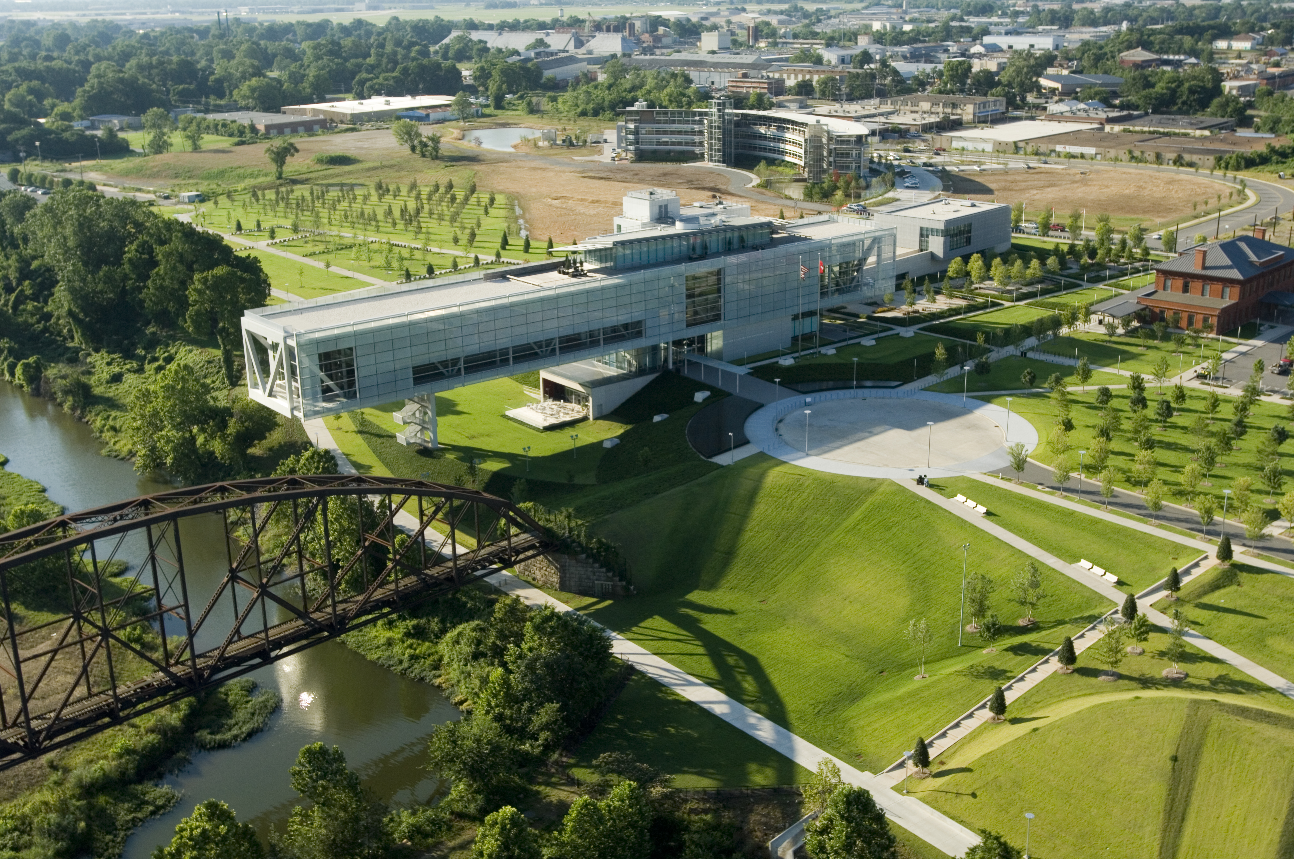 Aerial view of the Clinton Library showing the full building as well as the courtyard next to it and the pedestrian bridge in front.