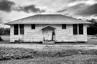 Alargewhitebuildinginthemiddleofafieldunderacloudysky