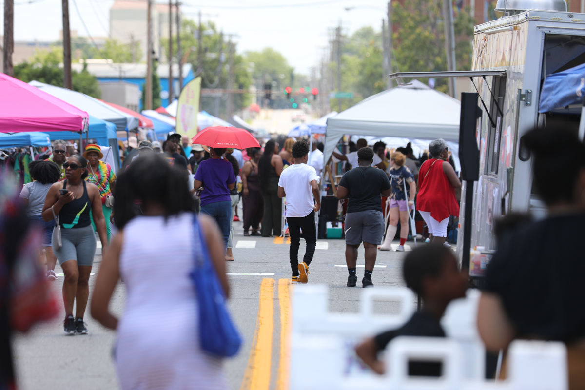 People walking along a street with market booths.