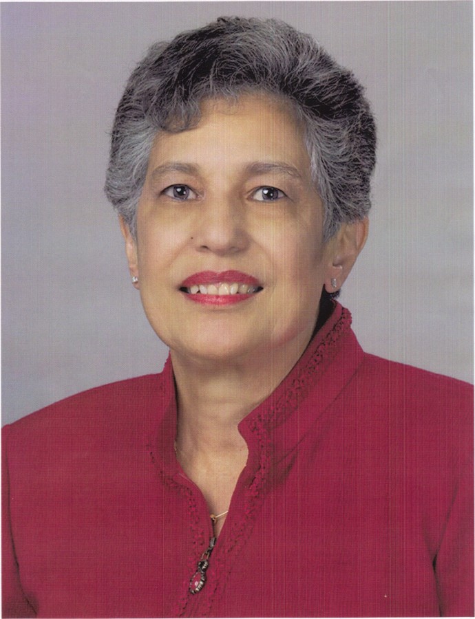 An older woman with short hair in a red blouse posing and smiling.